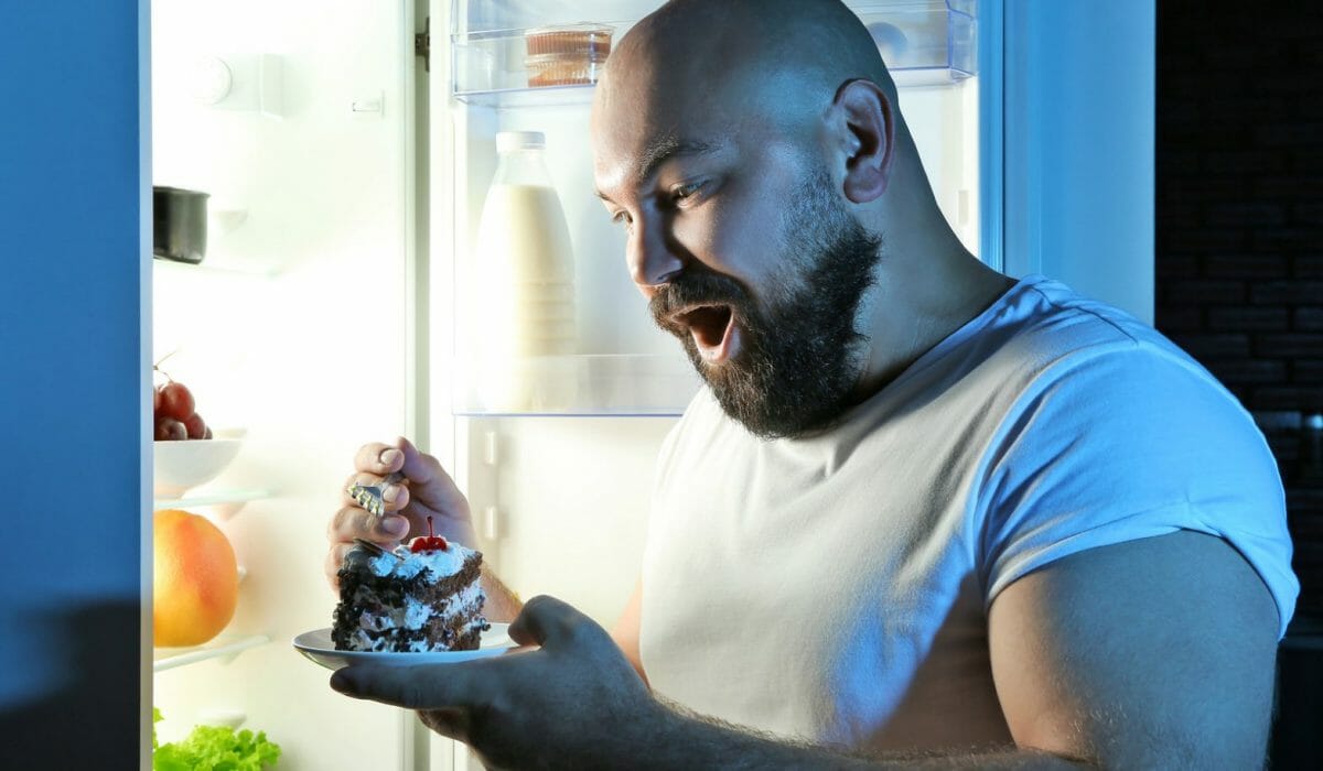 man eating at night in front of refrigerator 1